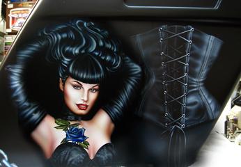 Bettie Page, AIRBRUSHED, posing with her hair up in long gloves & wearing a laced bra & in front of a leather corset on a custom Harley saddle bag